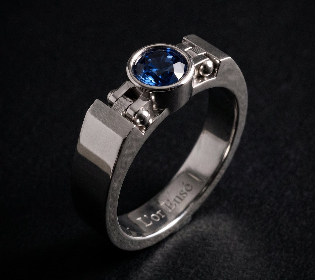 Rivet Signet Ring in platinum, a round sapphire framed by a solid metal collar between two fluted, rivet-set shoulders